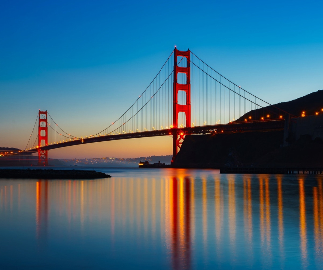 The Golden Gate Bridge at sunset with water reflections